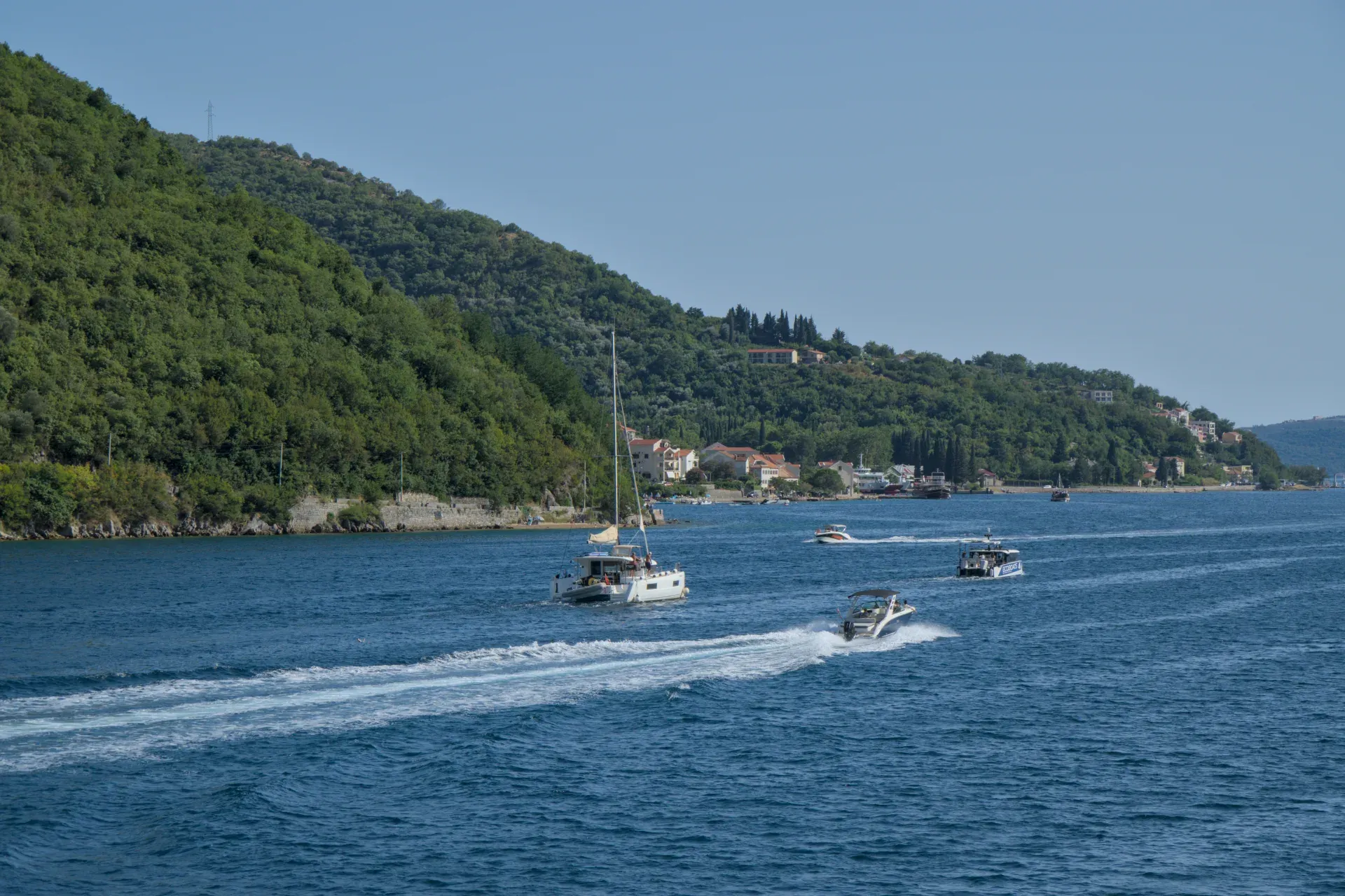 Barche nella Baia di Kotor, Montenegro, con colline verdi sullo sfondo, fotografia di acqua blu per design d'interni.