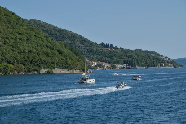 Boats in Kotor Bay, Montenegro, with green hills in the background, blue water photography for interior design.