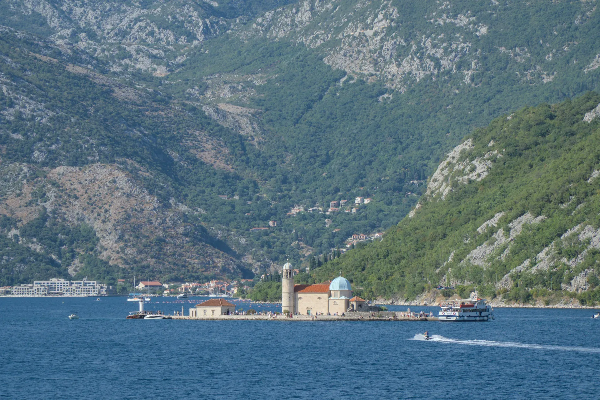 Blick auf die Inselkirche Gospa od Škrpjela in Kotor, Montenegro mit Bergen und Meer.