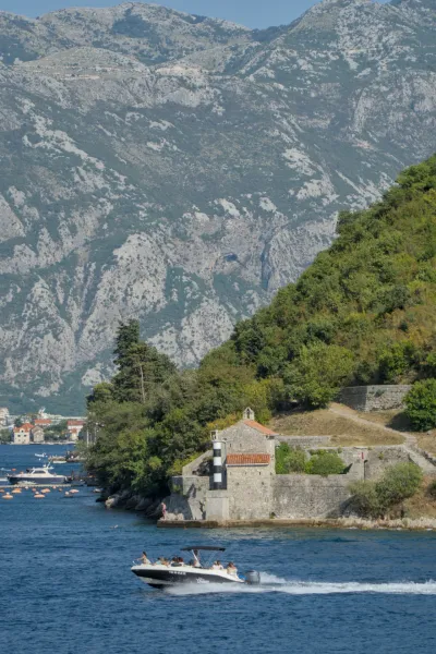 A lighthouse on the coast of Kotor Bay, Montenegro, with a boat on the water.