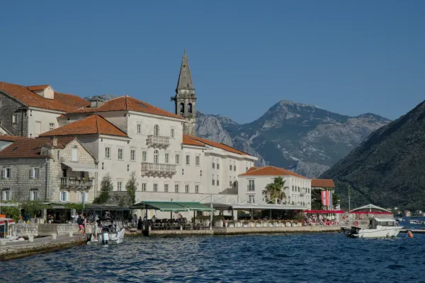 Sunset in Perast, Montenegro, with golden light on historic buildings and mountains in the background.