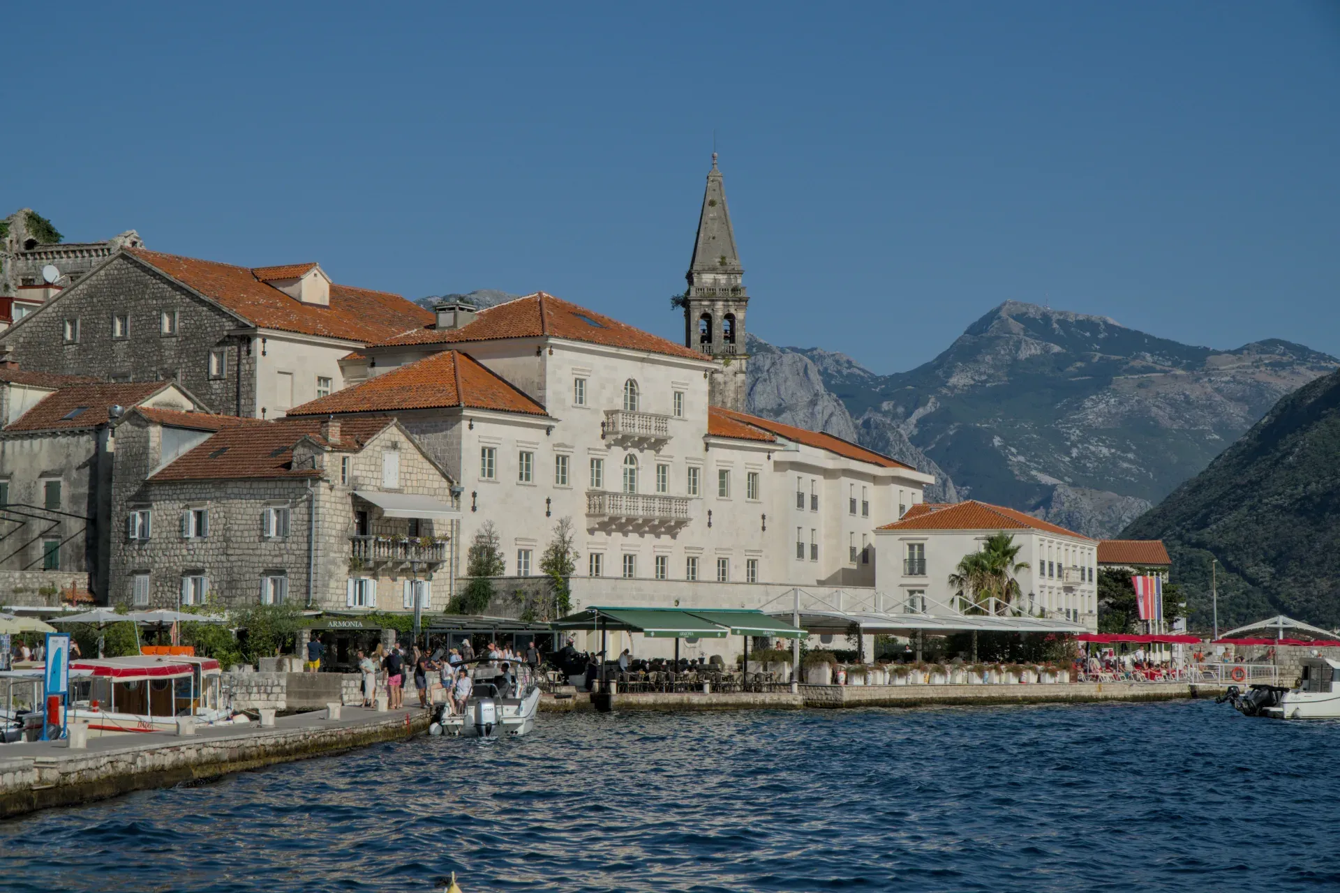 View of Perast in Montenegro at sunset with historic buildings and mountains in the background.