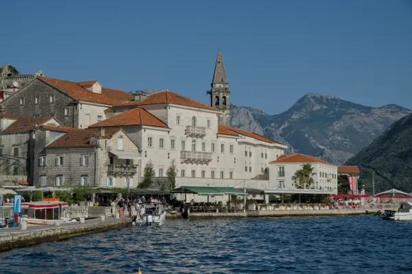 View of Perast in Montenegro at sunset with historic buildings and mountains in the background.