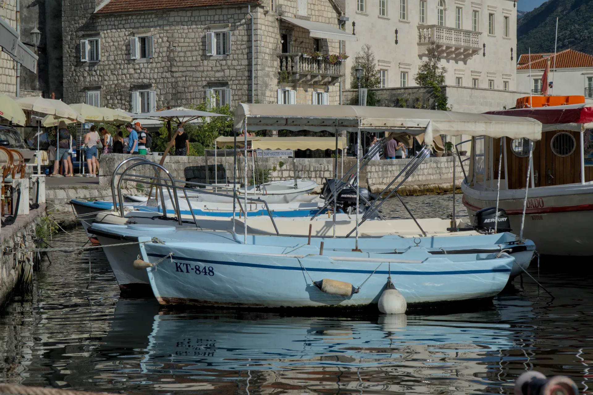 Slike čamaca u luci Perast, Crna Gora, sa kamenim zgradama u pozadini.