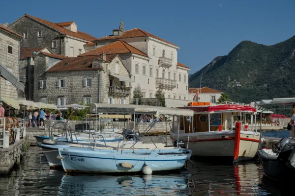 Boat in front of historical architecture in Perast, Montenegro, in bright sunshine.
