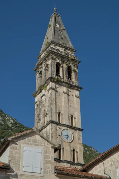 A detailed portrait of the old stone bell tower of Perast, Montenegro, at dusk.