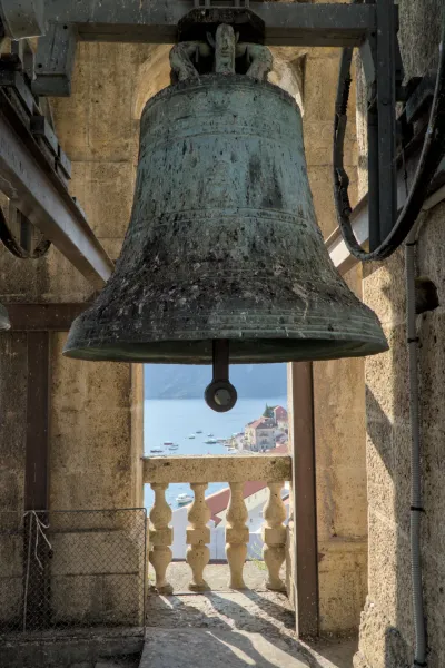 An old bell in a stone tower overlooking the coastal town of Perast and the sea in Kotor.