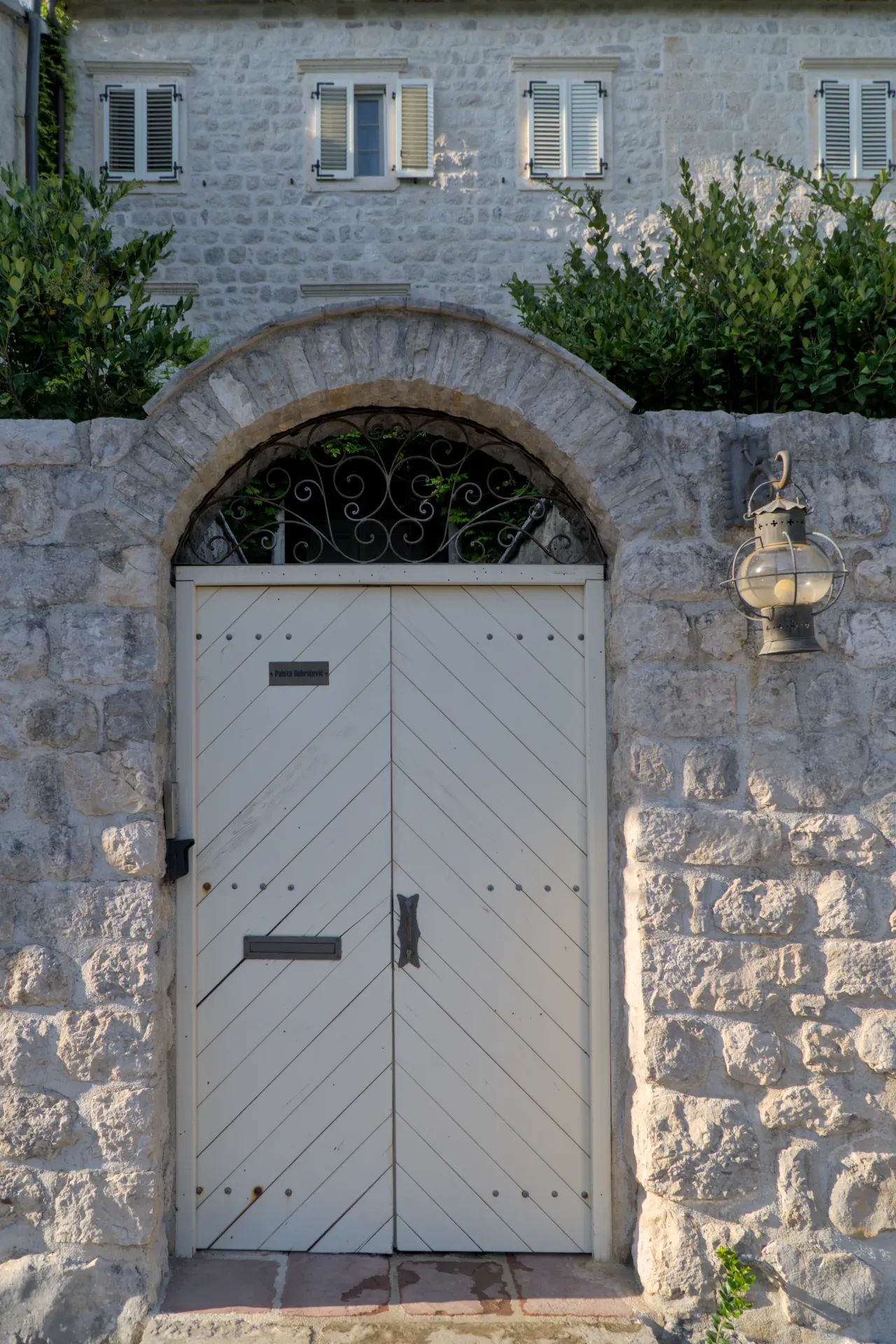 Gate in Perast, Montenegro, with ornate lamp and stone architecture.