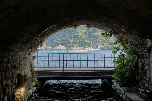 Sea view with boat and architecture through a stone arched passage in Perast, Kotor.
