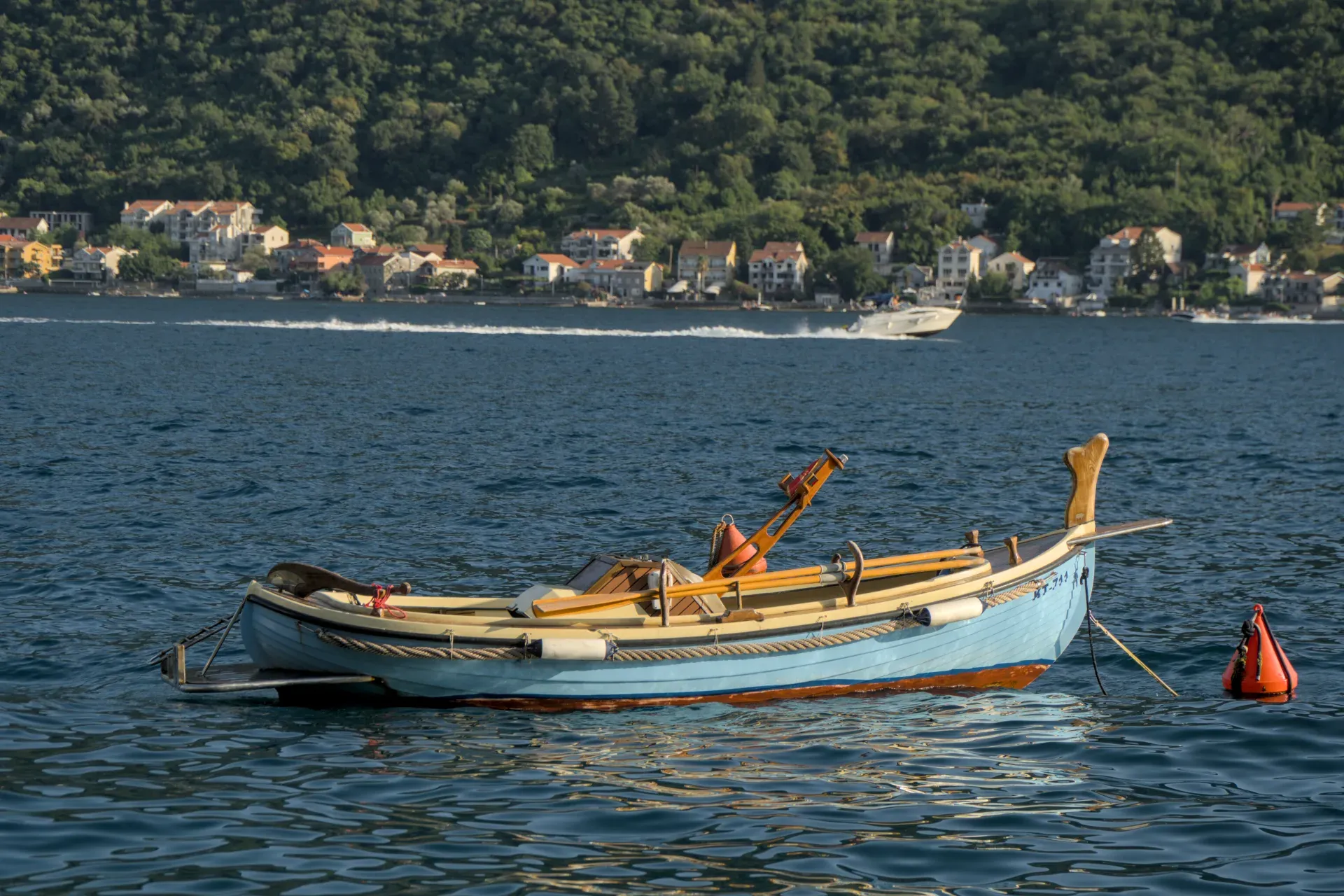 Un barco azul claro flota en las tranquilas aguas de la Bahía de Kotor, cerca de Perast, Montenegro.