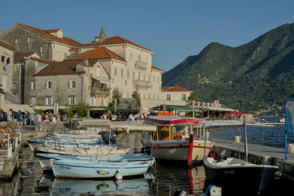 Perast, Montenegro, captured during the golden hour, featuring boats in the harbor and mountains beyond.