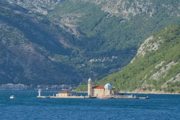 The island church of Our Lady of the Rocks on the water, with lush mountains in Kotor, Montenegro.