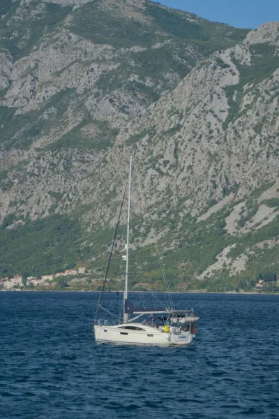 A white yacht sailing in Kotor Bay against a mountainous backdrop, fine art for coastal interiors.