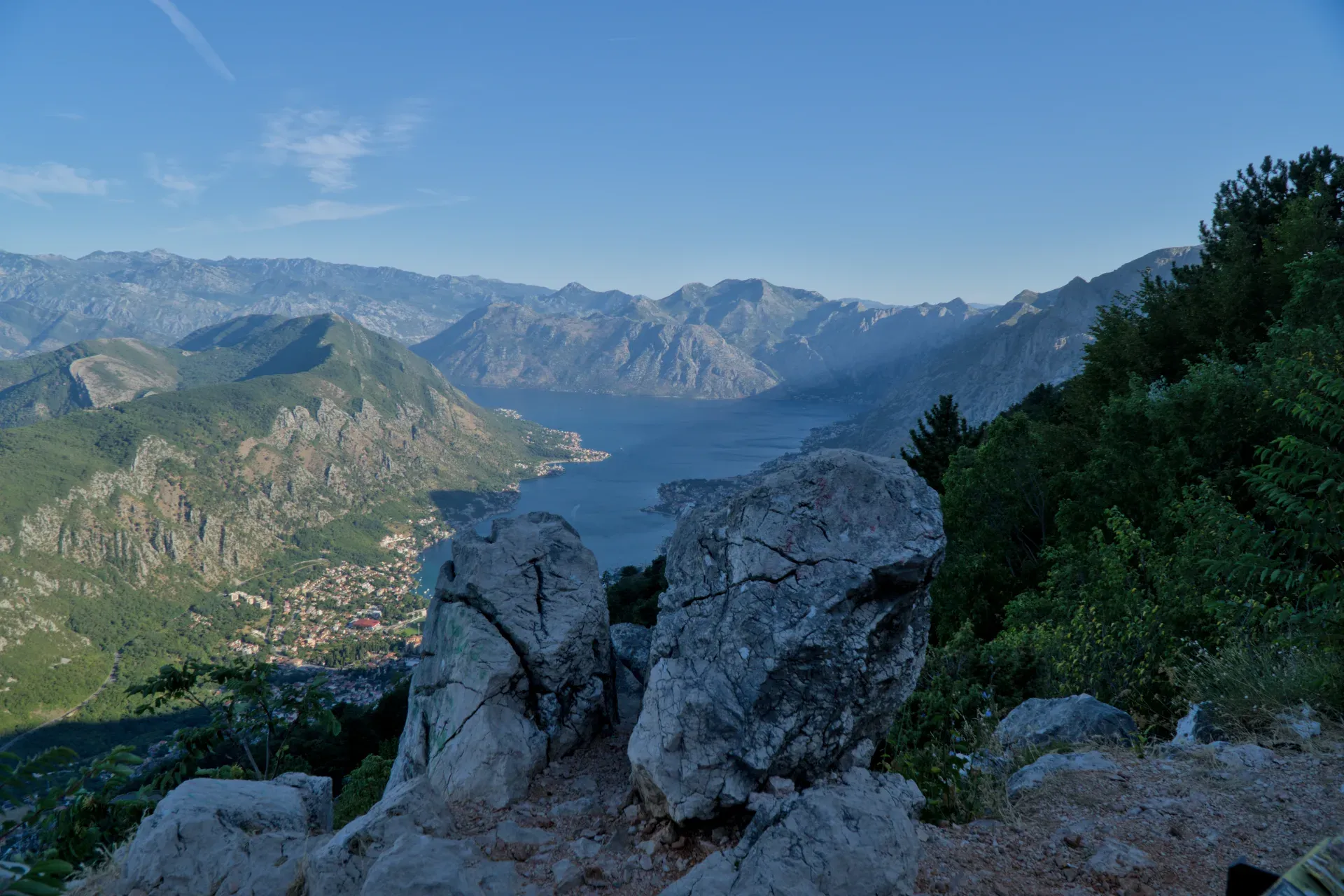 Morning scene of Kotor Bay, Montenegro, viewed from a mountain road with a rocky foreground.