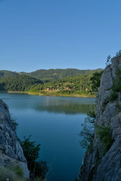 Sunset at Lake Zaovine, Serbia, with forested hills and rocky foreground.