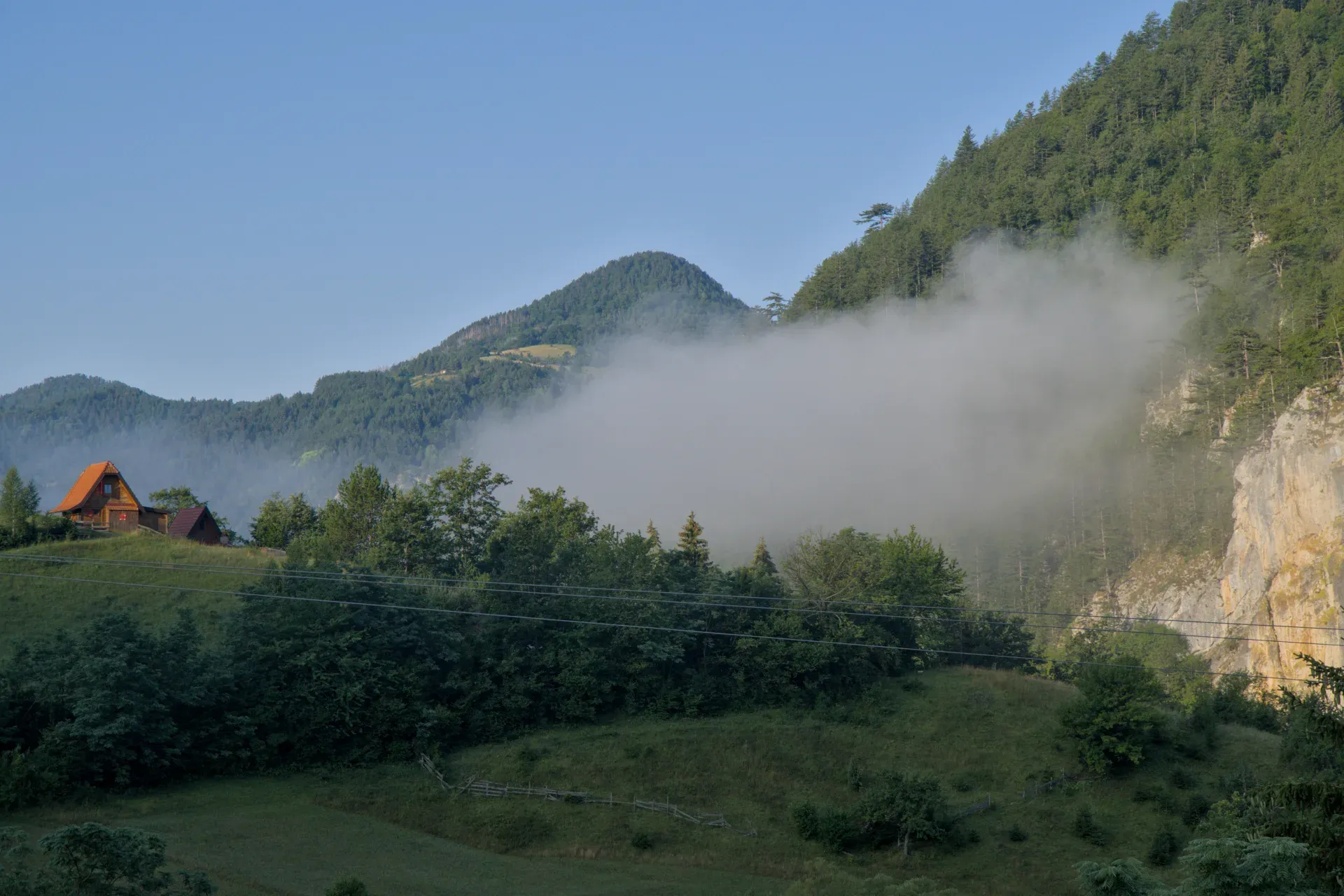 Jutarnja magla u planinama Zaovine, Srbija, sa kućama i šumama.
