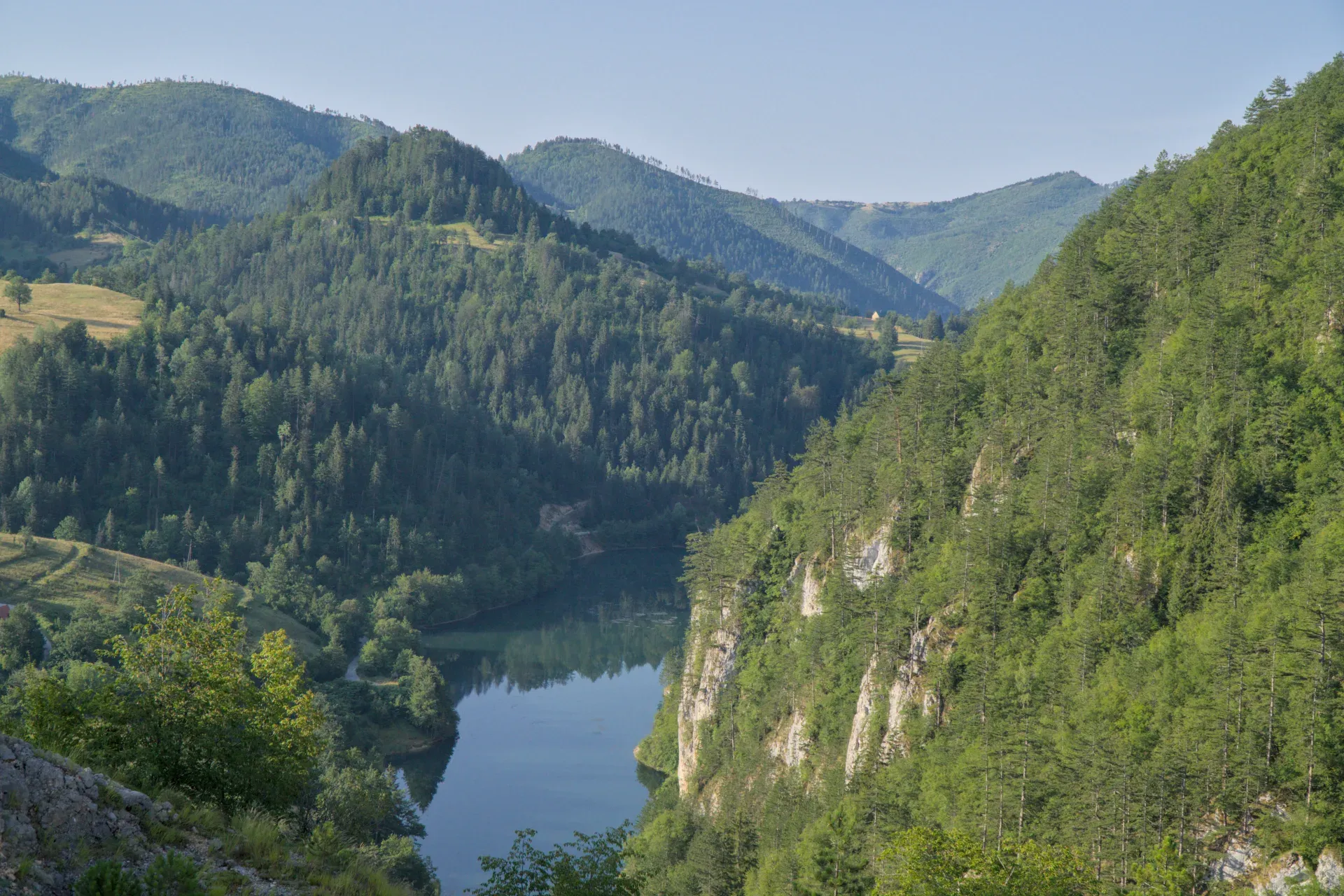 Jezero Spajići, pogled sa brane Lazića u Nacionalnom parku Tara, sa bujnim zelenim planinama i mirnom vodom.