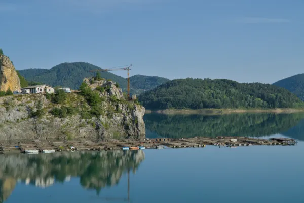 Zaovine Lake Serbia at dawn with calm waters reflecting green mountains, ideal for fine art wall decor.