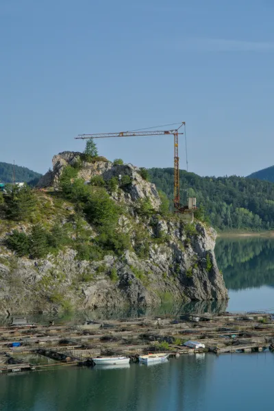 Morning view of Zaovine Lake with a crane on a rock and floating fish farms in the foreground.