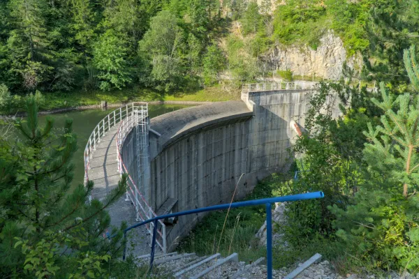 A concrete dam at Spajići Lake in Tara National Park, Serbia, surrounded by lush green trees and water.