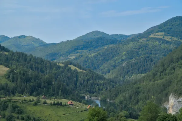 Mountain landscape featuring Spajići Lake, a dam, and a village in Serbia's Tara National Park.