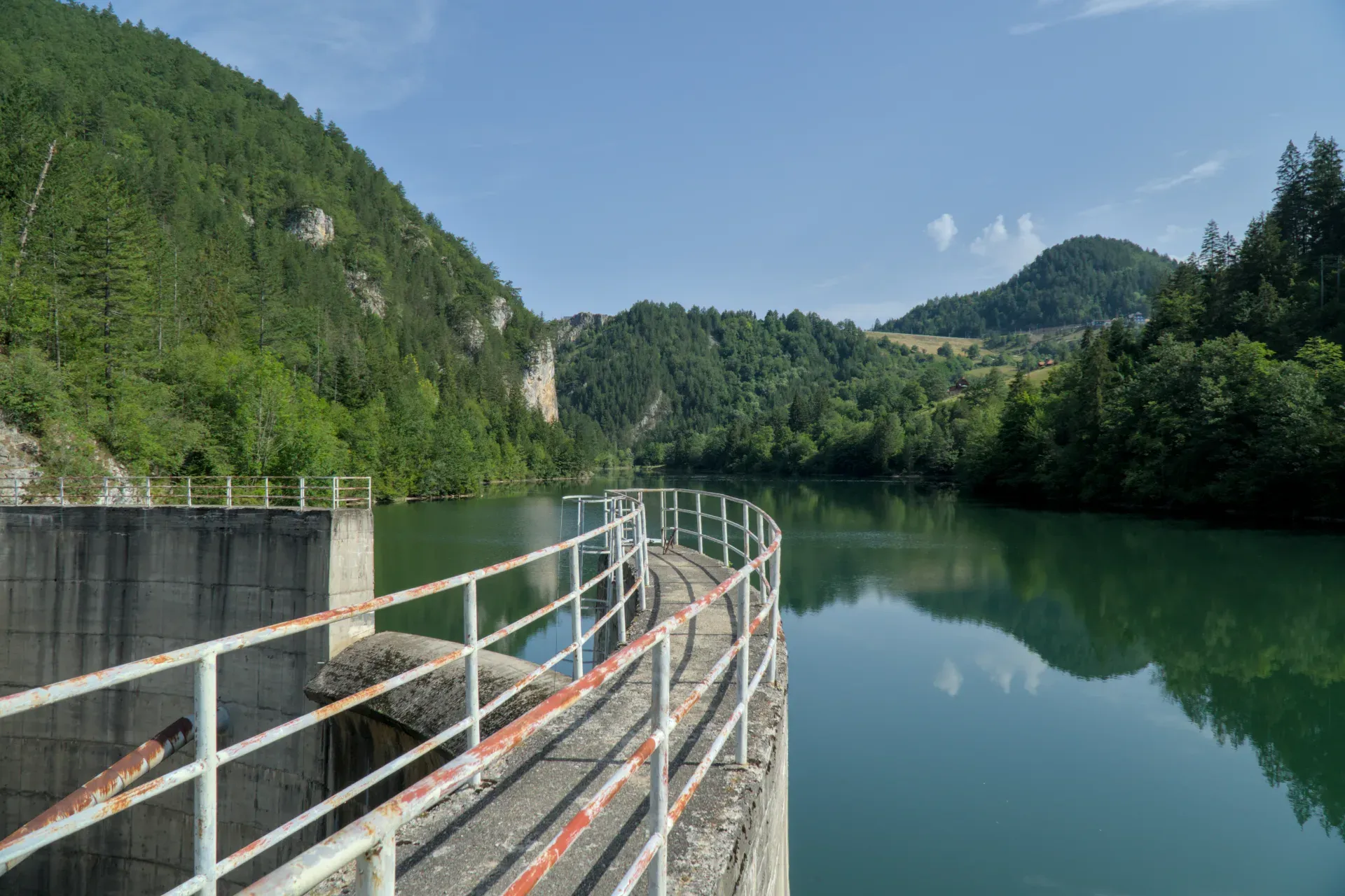 Die Spajići-Talsperre in Serbien mit ihrem geschwungenen Steg und der umliegenden grünen Berglandschaft.