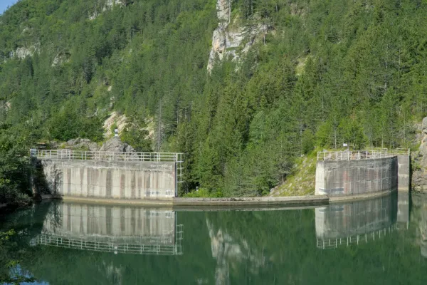 The dam at Spajići Lake in Zaovine, Serbia, reflecting in the calm water, surrounded by green mountains and forest.