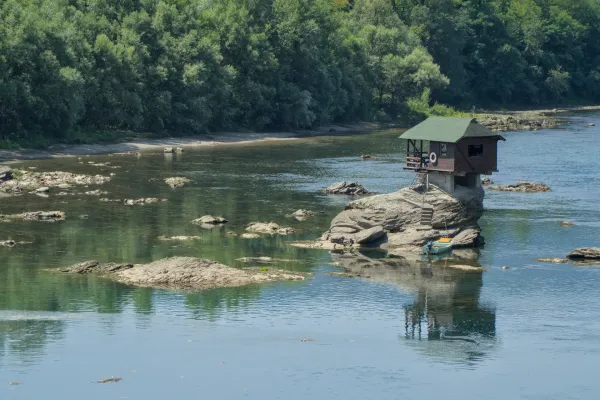 A small wooden house sits on a rock in the middle of the Drina River, Serbia.
