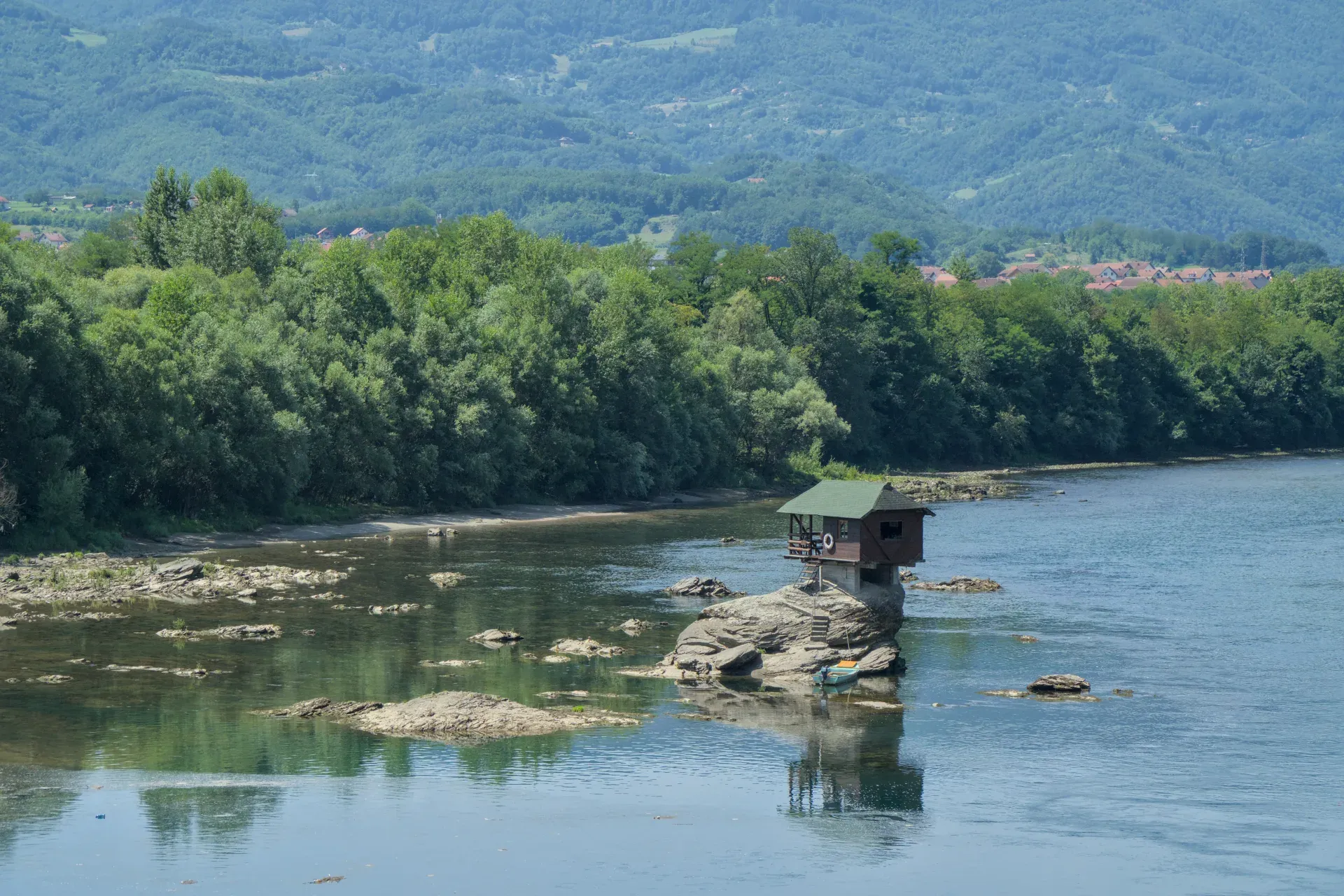 La "домик на Дрине" (Maison sur la Drina) se dresse sur un rocher dans la rivière Drina en Serbie, au milieu d'un paysage naturel luxuriant.