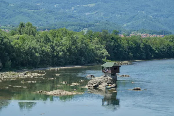 The "домик на Дрине" (House on the Drina) stands on a rock in Serbia's Drina River, amidst a lush natural landscape.