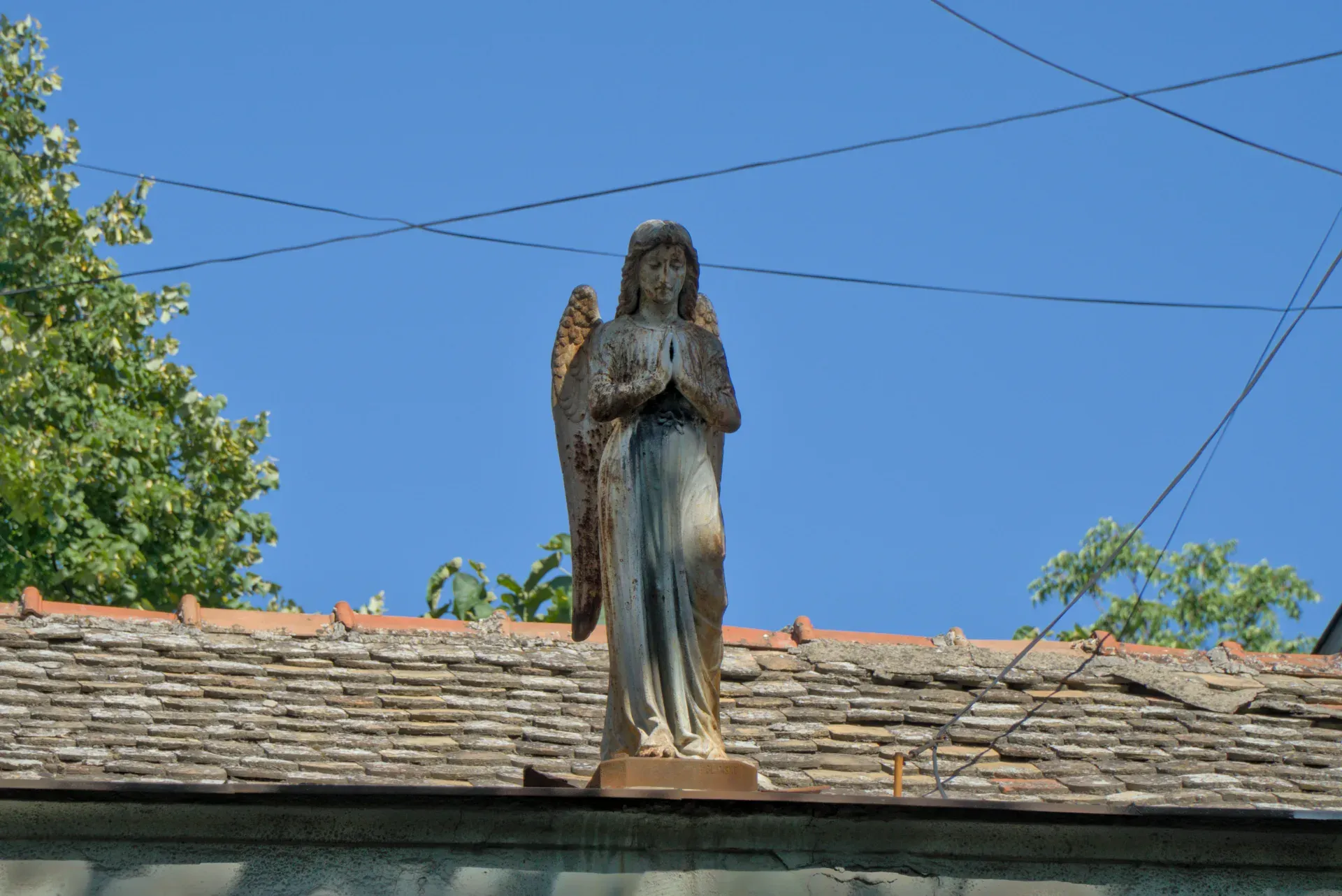 Una escultura de un ángel en el tejado de una casa en Novi Sad, Serbia, contra un cielo azul.