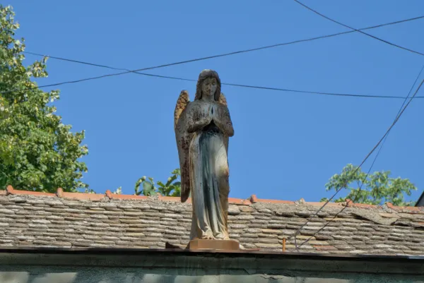 A sculpture of an angel on the roof of a house in Novi Sad, Serbia, against a blue sky.