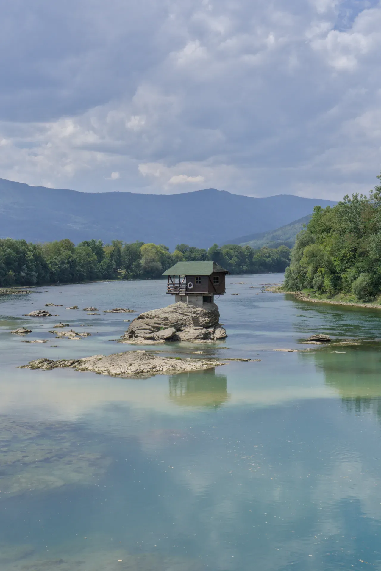 A house on a rock in the Drina River under dramatic clouds, Bajina Bašta, Serbia.