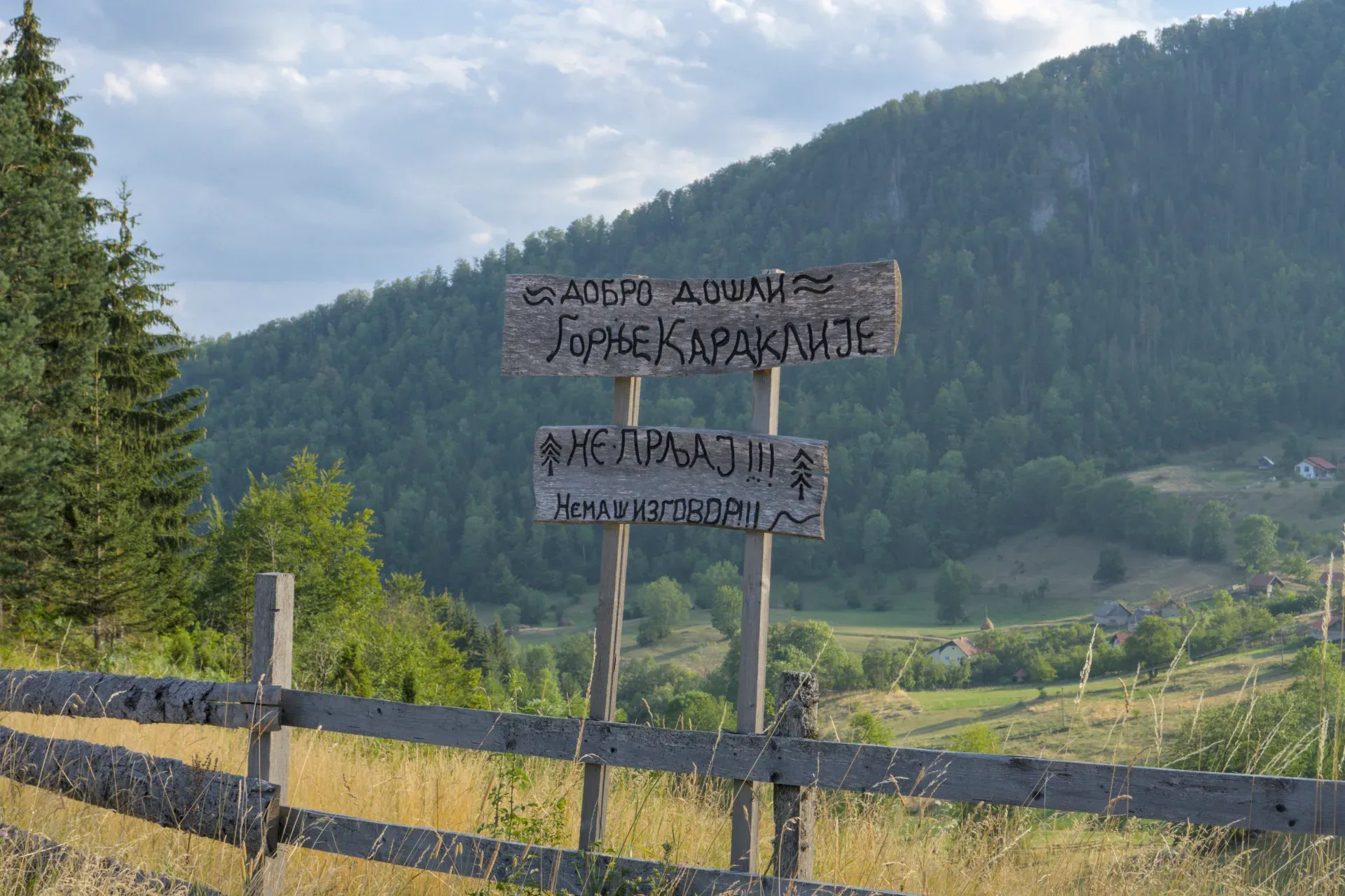 Un divertido cartel serbio con escritura pintada a mano en Gornje Karajlić, Parque Nacional Tara, Serbia, contra un telón de fondo montanñoso.