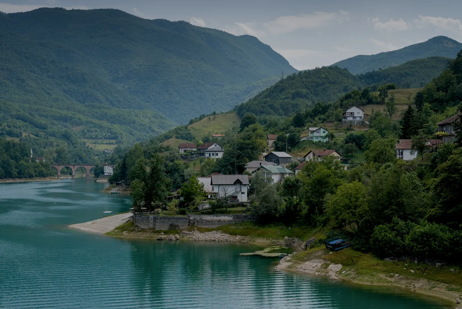 Scenic landscape with a turquoise lake and hillside homes on the road to Mostar.
