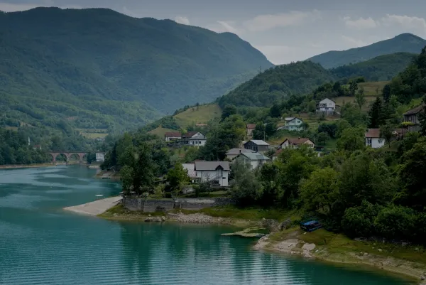 Scenic landscape with a turquoise lake and hillside homes on the road to Mostar.