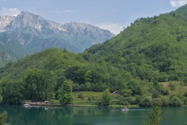 Scenic route from Sarajevo to Mostar: A mountain lake with a boat and green hills under a cloudy sky.