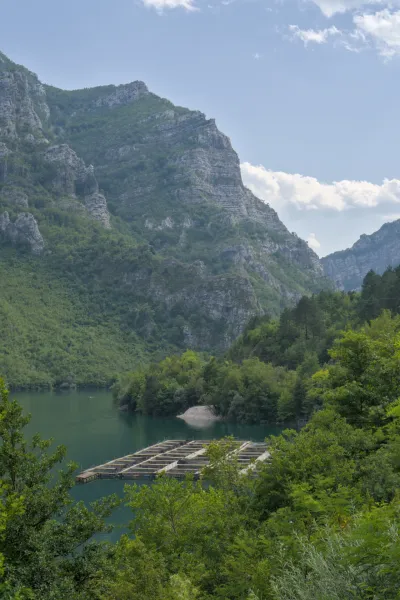 A lake with a fish farm set against majestic mountains, captured on the road from Sarajevo to Mostar.