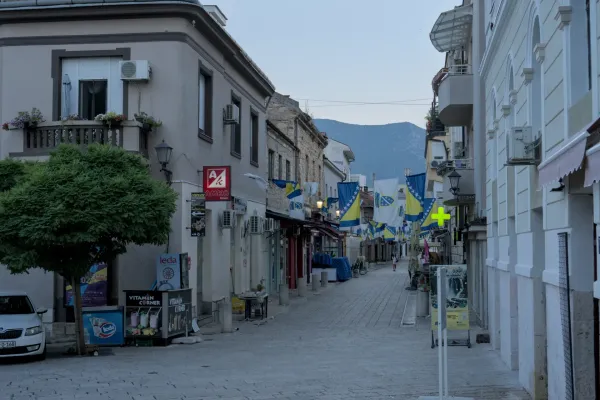 Early morning light in Mostar's Old Town, featuring national flags and cobblestone streets.