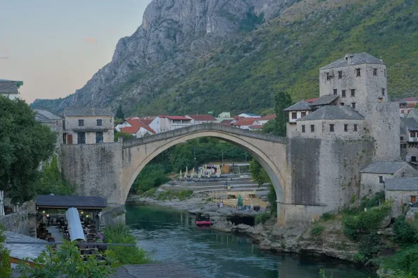The Stari Most bridge in Mostar, Bosnia and Herzegovina, before sunrise, with the Neretva River and historic buildings.