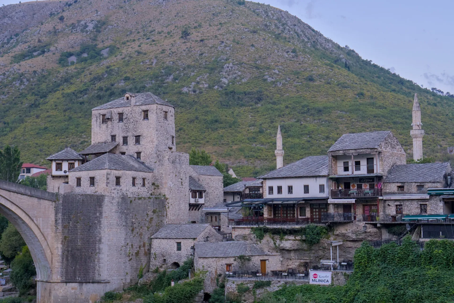 Early morning light over Mostar's Old Town, showcasing stone architecture and minarets against a hilly backdrop.