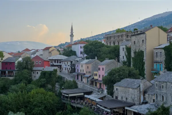 Landscape view of Mostar's old town at dawn, featuring traditional architecture and a minaret.