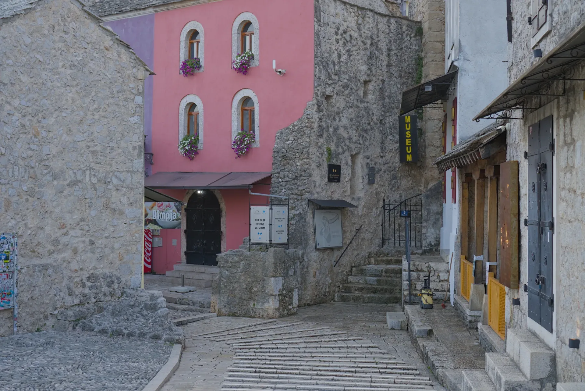 Prazne ulice starog Mostara u rano jutro sa roze i kamenim zgradama.