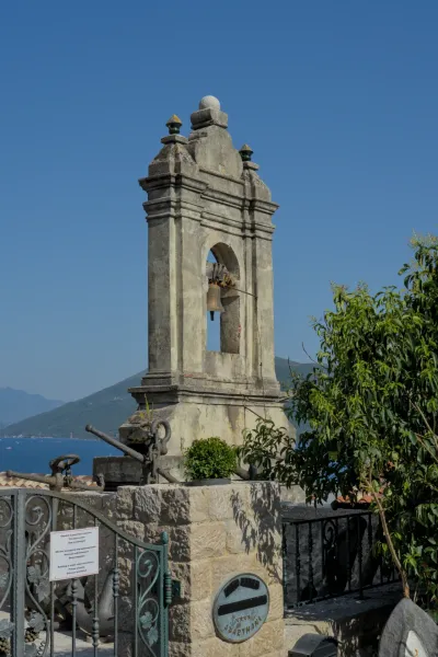 An old stone bell tower featuring a bell, located in the old town of Herceg Novi.