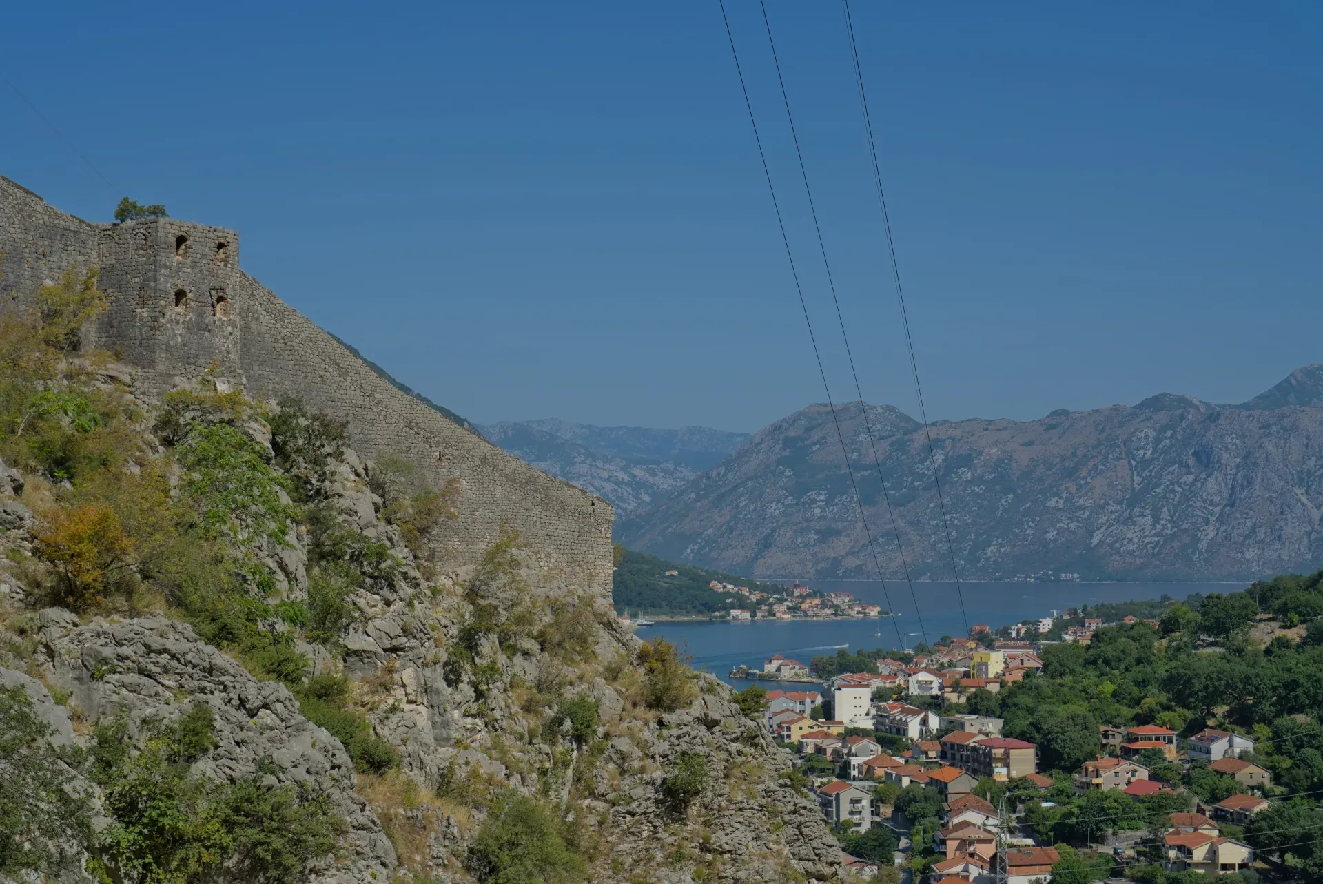 Vue depuis le mur de la forteresse de Kotor sur Dobrota et Prčanj, avec montagnes et mer au loin.