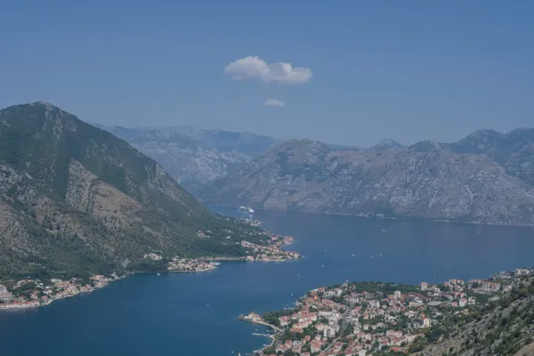Aerial view of a cruise ship entering Kotor Bay, overlooking the coastal towns of Dobrota and Prcanj.