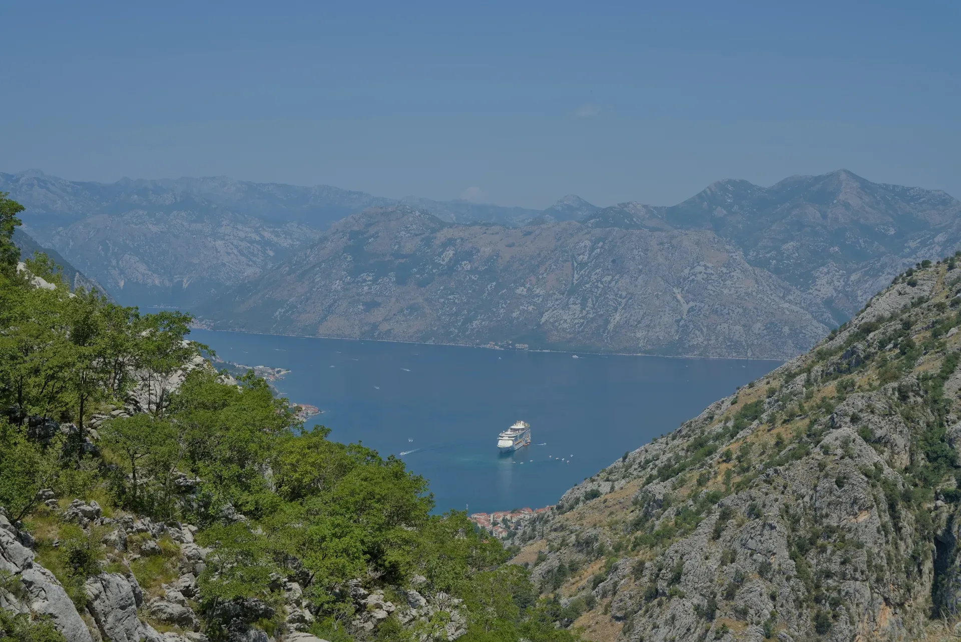 View of Kotor Bay in Montenegro from a mountain through rocks, with a cruise ship in the water.