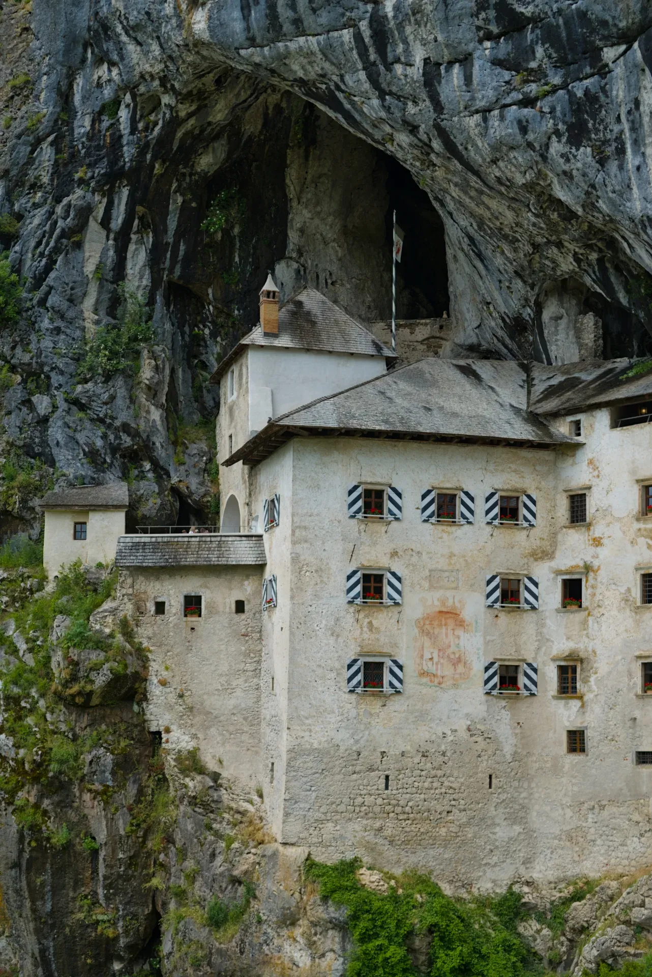The старинный предъямский замок в скале, an ancient castle built into a rocky cliff face in Slovenia, showcasing architectural detail against natural stone.