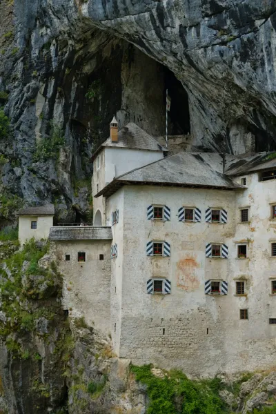 The старинный предъямский замок в скале, an ancient castle built into a rocky cliff face in Slovenia, showcasing architectural detail against natural stone.