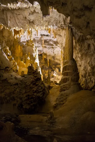 Otherworldly underground landscapes of Postojna Cave with stalactites and stalagmites in warm light.